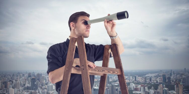 Young businessman looking for opportunities through the spyglass standing on the stairs.  Cloudy sky and city around.